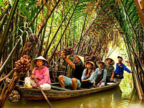 Cyclists riding through quiet village lanes on the Mekong Delta bike tour